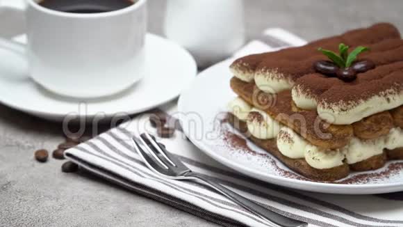 陶瓷盘子上的经典提拉米苏甜点牛奶或奶油混凝土背景上的咖啡杯视频的预览图
