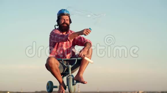 疯狂有趣的人在天空背景上骑自行车有趣的人在乡间小路上骑着儿童自行车有趣的男人搞笑视频的预览图