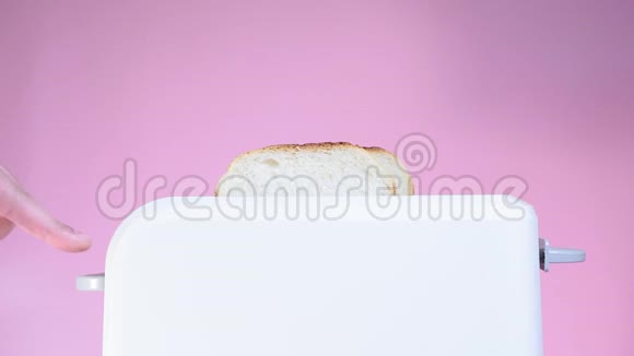 烤面包用烤面包机在厨房准备早餐粉色背景的白色烤面包机视频的预览图