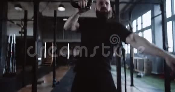 运动的年轻胡须白人男子在极端功能锻炼举重壶铃在大型健身房慢动作视频的预览图