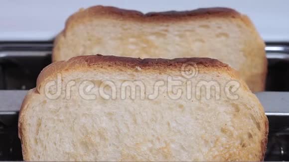 烤面包从白色烤面包机上跳出来糕点加工过程中的特写镜头视频的预览图