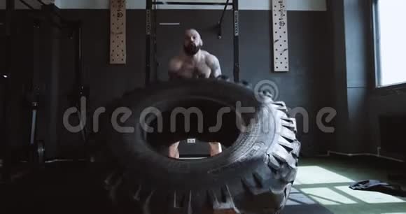 极限功能训练运动年轻的白种人男子举起巨大的轮胎在大型健身房缓慢运动视频的预览图