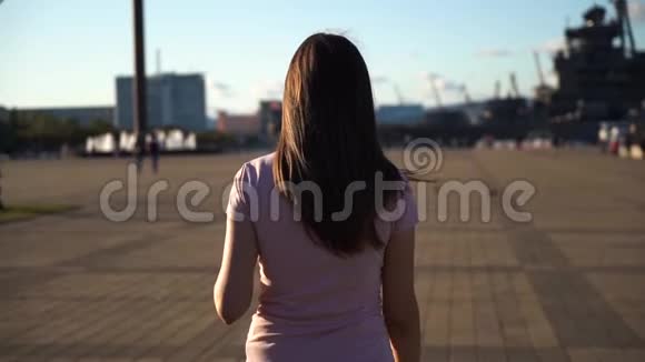 年轻女子穿着粉红色的衬衫走在河堤上手里拿着咖啡翻过来对着镜头看视频的预览图