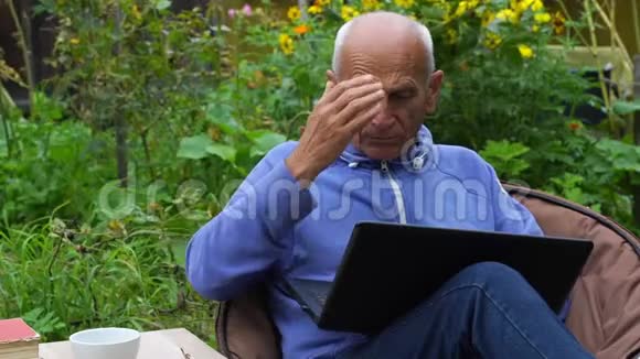 退休老人用手提电脑慢动作在椅子上按摩视频的预览图