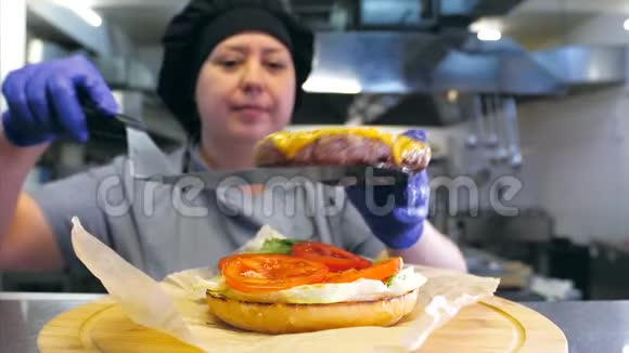 女厨师在餐厅的厨房里准备了美味的汉堡和奶酪视频的预览图