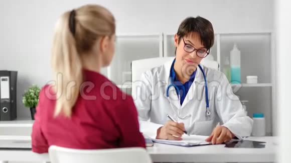 戴眼镜穿外套的女医务工作者在咨询过程中与女病人交谈视频的预览图