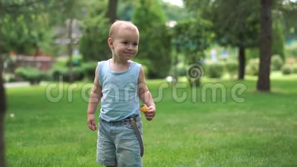 一个男孩兴高采烈地穿过公园手里拿着一片叶子慢吞吞地跑着视频的预览图