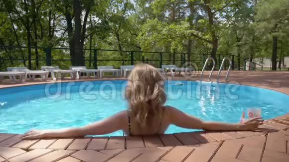 性感的金发女郎正在酒店的游泳池里享受夏日的好天气视频的预览图