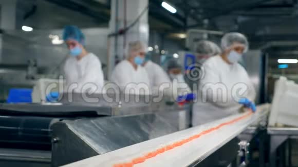 工厂工人正在把鱼产品从传送带上移走视频的预览图