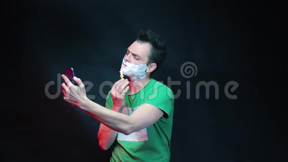 一个男人在看智能手机的屏幕时刮脸视频的预览图