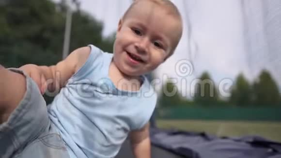 蹦床上微笑的婴儿缓慢地用脚踢摄像机视频的预览图