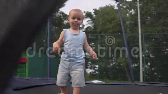一个小男孩努力地缓慢地跳上公园里一个封闭的蹦床视频的预览图
