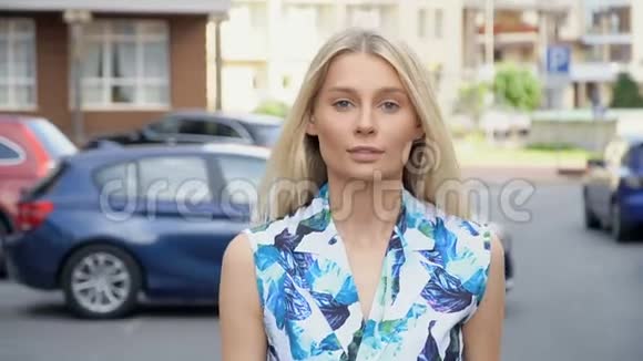 穿着夏季套装的金发女郎在停车场摆姿势摄像机接线女子步行视频的预览图