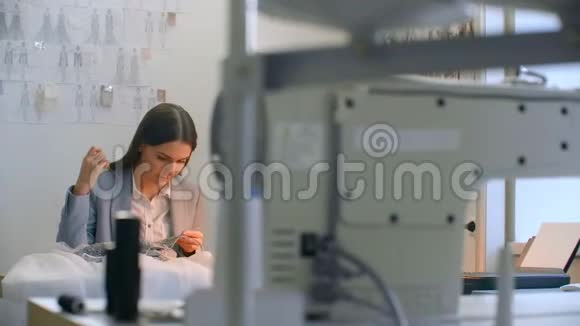 缝纫车间的女孩坐在桌旁手工缝制珠子和首饰缝制礼服和装饰晚礼服视频的预览图