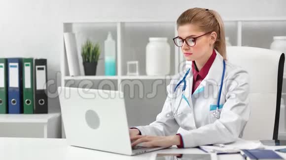 年轻漂亮的女医生在现代诊所用笔记本电脑工作视频的预览图