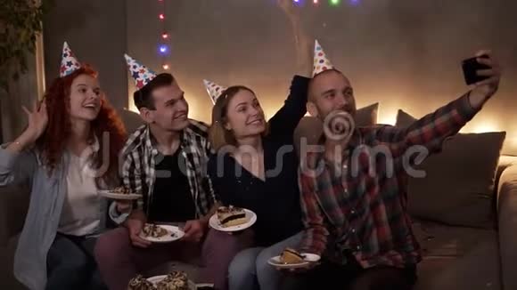 快乐的年轻的朋友或两对夫妇在庆祝生日的时候他们一起坐在节日的圆锥体上视频的预览图