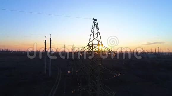 橙色日落和天空背景下的高压电线塔和电力线路的鸟瞰图视频的预览图