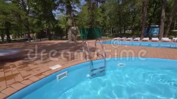 幸福的年轻女子正在进入松林度假酒店的小游泳池视频的预览图
