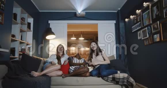 开朗微笑多民族女性朋友在家一起看电影笑谈吃零食慢动作视频的预览图