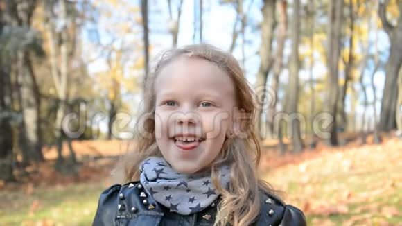 秋天公园里一个美丽的五岁小女孩在黄色树叶的背景下的欢快的画像视频的预览图