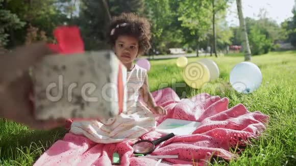 快乐的非洲裔小女孩在生日时玩礼物盒视频的预览图