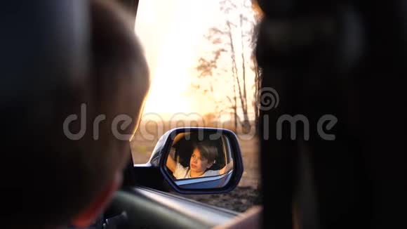 家庭旅行一家人在公路上开车镜子里的倒影日落时间视频的预览图