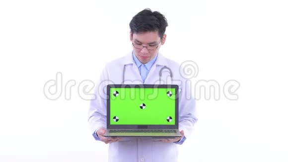 快乐的亚洲青年医生一边说话一边拿笔记本电脑视频的预览图