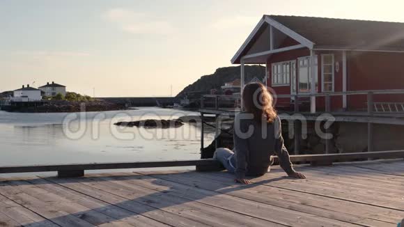日落时分一位年轻女子坐在码头上欣赏风景视频的预览图