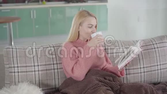 迷人的高加索女人坐在家里的书和一杯热茶或咖啡的肖像可爱的女孩视频的预览图