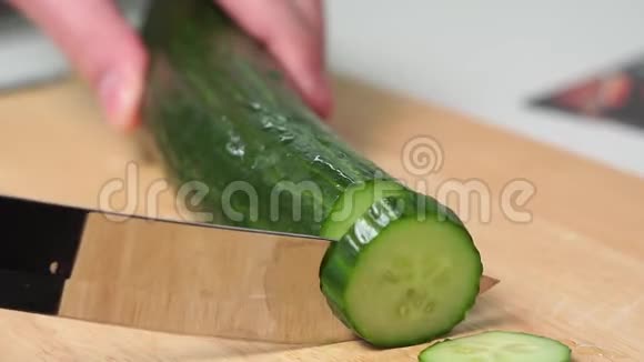 切黄瓜一个人用手在木切割板上用刀切黄瓜沙拉的配料视频的预览图