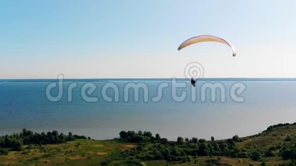 绿色的土地和快速滑翔飞行在上面人滑翔伞美丽的自然背景视频的预览图