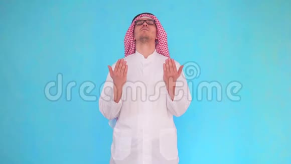 阿拉伯人站在蓝色的背景上向上帝祈祷视频的预览图