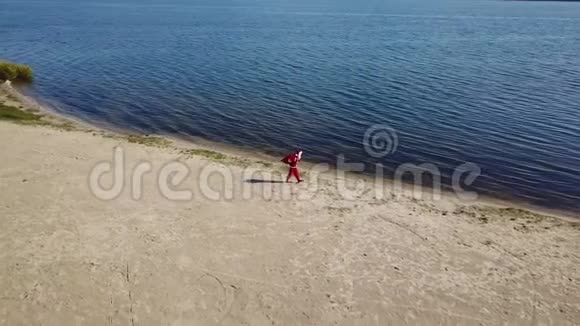 疲惫的圣诞老人带着一袋礼物沿着湖岸走顶部视图视频的预览图