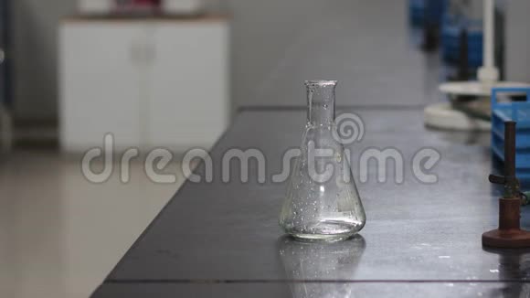 将塑料洗瓶机中的化学液体倒入化学黑色花岗石板上的锥形烧瓶中视频的预览图