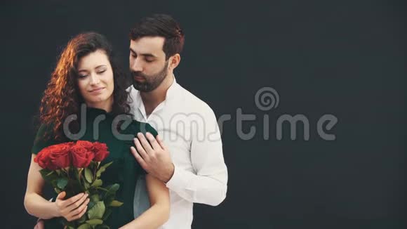 快乐的卷发女孩捧着一束玫瑰浪漫的年轻人抚摸她的肩膀视频的预览图