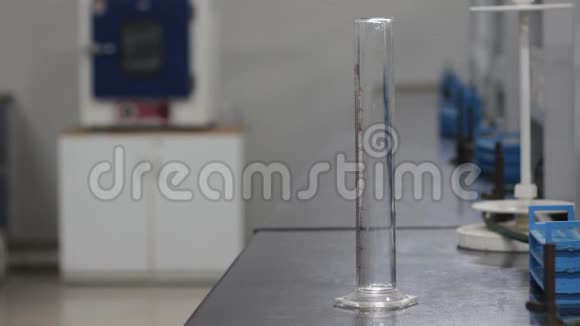 化学实验室将液体化学物质从量筒倒入黑色花岗石板上的锥形烧瓶中视频的预览图