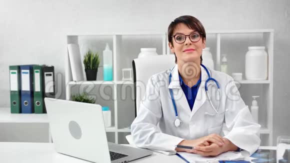 一位身着制服戴眼镜的成熟女医生在现代工作场所的肖像视频的预览图