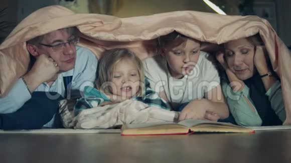 一个男孩和一个女孩正和他们的祖父母在地板上看书视频的预览图
