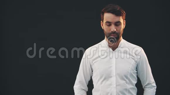 年轻自信的男人穿着白色衬衫站在黑色的背景上摆姿势保持双手视频的预览图