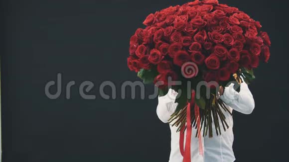 年轻人站着躲在一束红玫瑰的后面露出她那张受惊的脸张大了嘴巴和眼睛视频的预览图