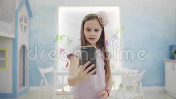 可爱的小女孩用一部智能手机在镜头前做视频翻译视频的预览图