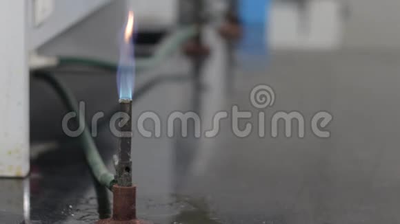 在化学实验室里双手穿着一件蓝色衬衫转动旋钮点燃本森燃烧器的火焰视频的预览图