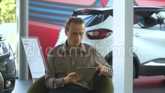 一位在汽车经销店买车的男士在平板电脑上做笔记视频的预览图