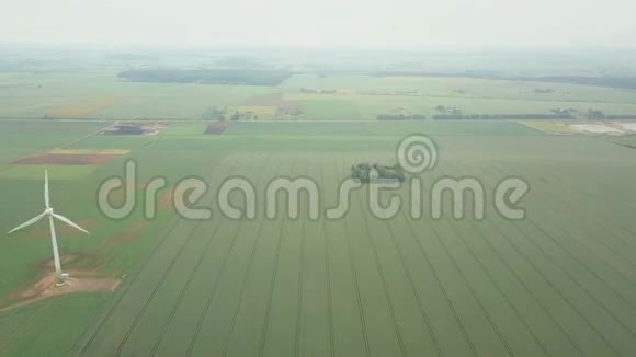 旋转风车在绿色的田野上晴天的风力涡轮机视频的预览图