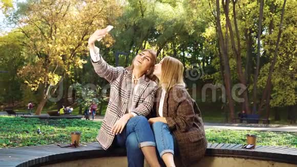 在公园里迷人的博客通过智能手机向粉丝发送亲吻视频的预览图