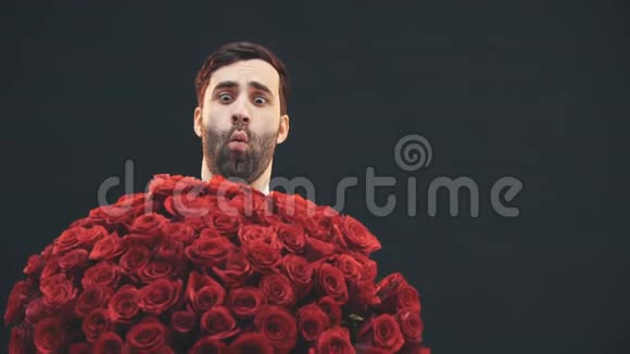 年轻人站着捧着一大束红玫瑰摇着它做着脸看起来很疯狂视频的预览图