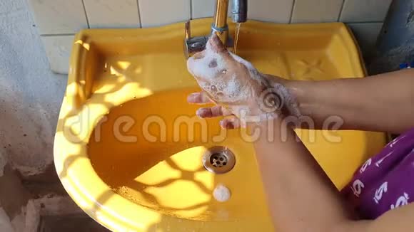 白天用肥皂在黄色洗手盆附近洗手突出手指尖防止病毒和视频的预览图