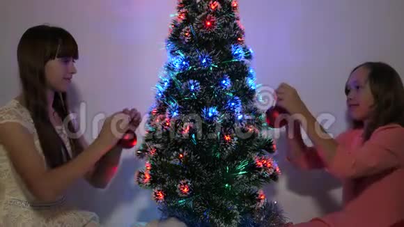快乐的童年概念孩子们用圣诞球装饰圣诞树小孩子玩圣诞树视频的预览图