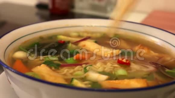 用筷子在韩国面条汤中加入切碎的辣椒片细节视频的预览图