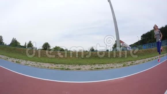 一位年轻漂亮的运动女子在城市体育场的摄像机前慢跑动作慢动作快视频的预览图